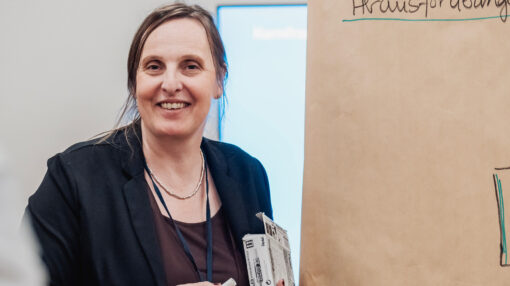 Das ist ein Bild von Anja Mücke neben einer Pinnwand.